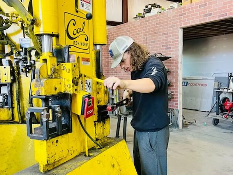 A student working the yellow ironworker press.